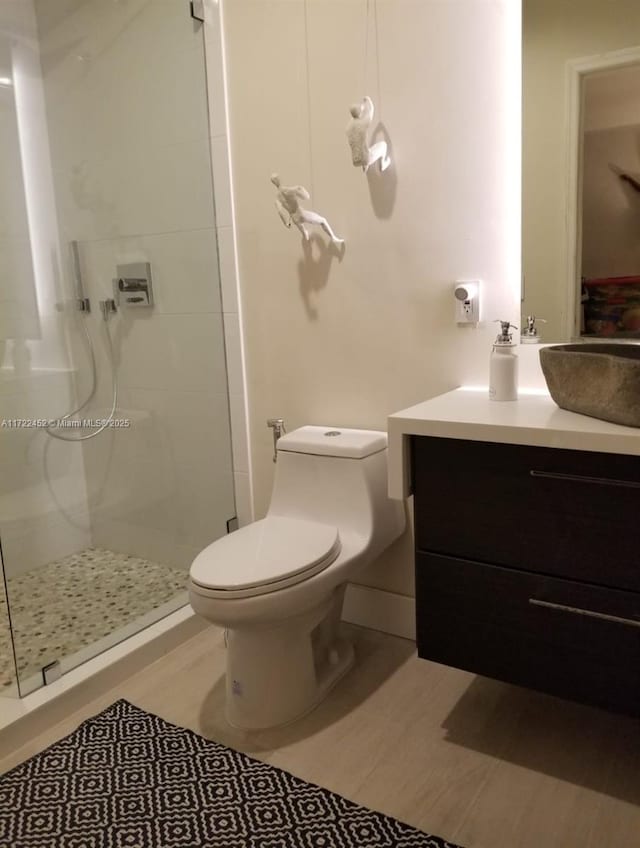 bathroom with a tile shower, vanity, and toilet