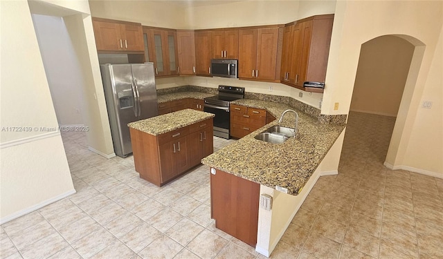 kitchen featuring a center island, sink, dark stone countertops, kitchen peninsula, and stainless steel appliances