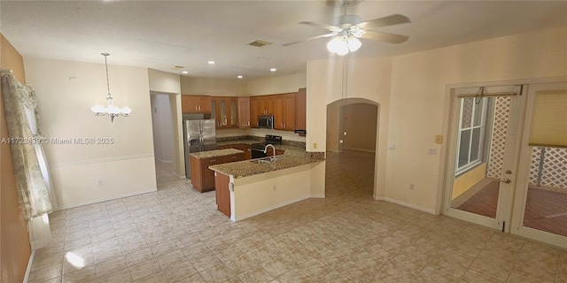 kitchen with kitchen peninsula, appliances with stainless steel finishes, ceiling fan with notable chandelier, sink, and decorative light fixtures