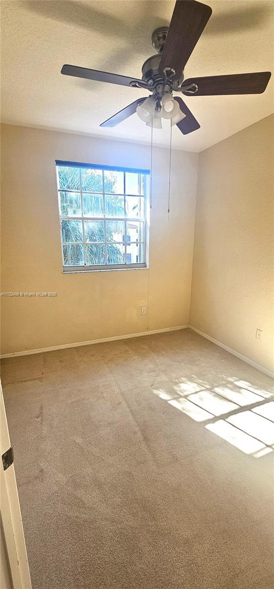 empty room with ceiling fan and carpet