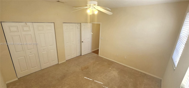 unfurnished bedroom with multiple closets, ceiling fan, and carpet