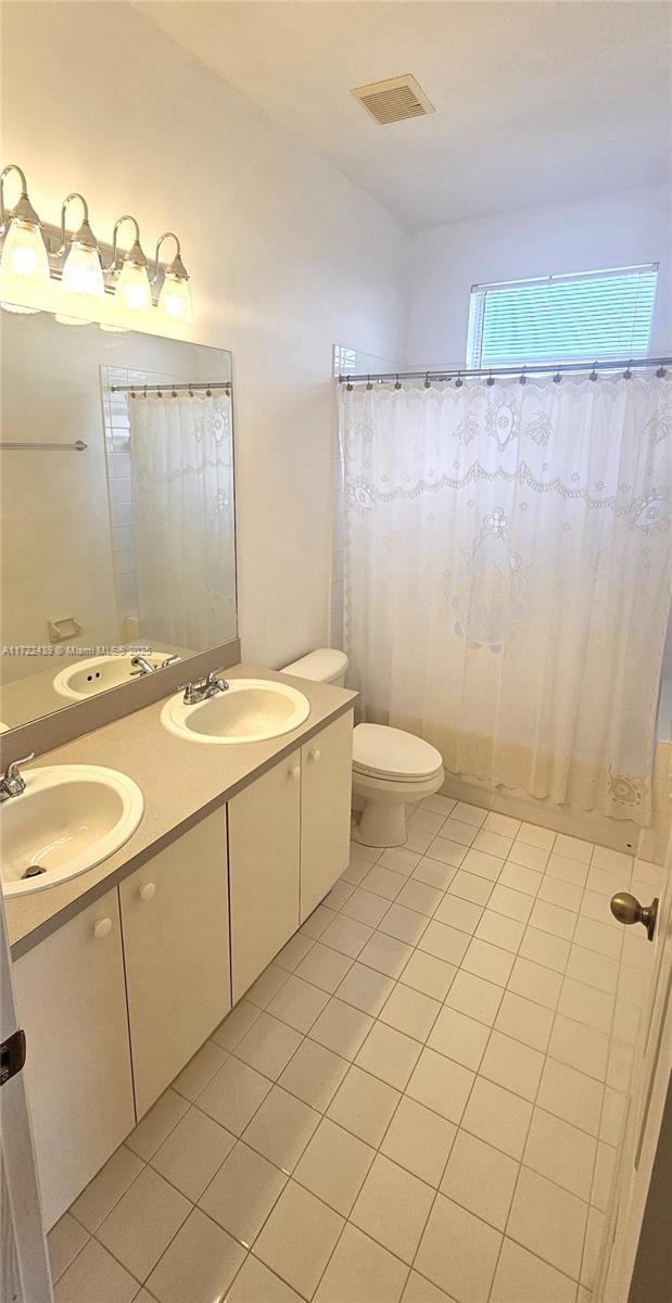 bathroom with tile patterned flooring, a shower with curtain, vanity, and toilet