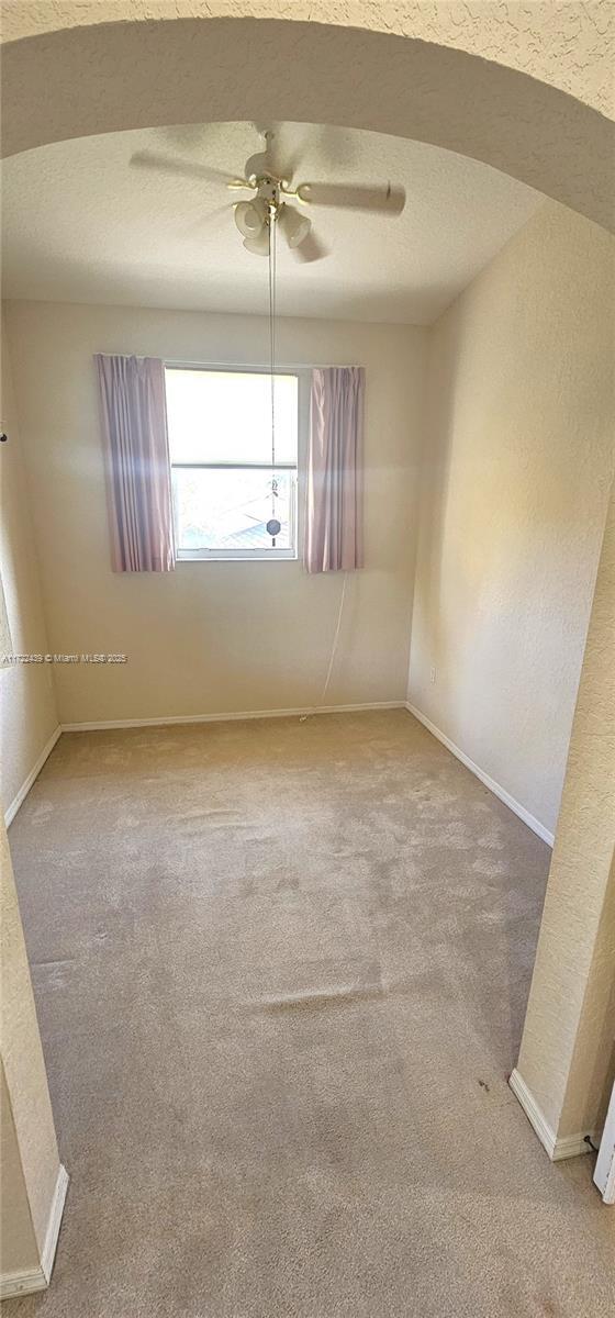 carpeted spare room with ceiling fan