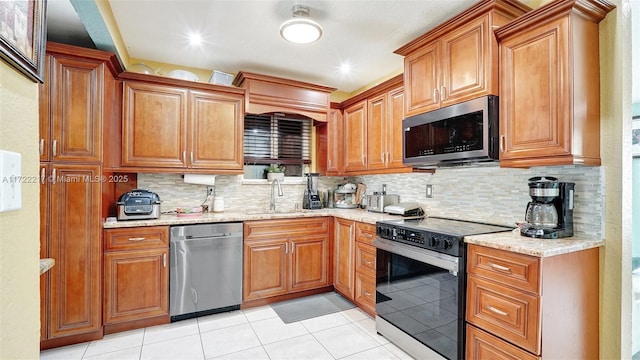 kitchen featuring decorative backsplash, sink, light tile patterned floors, and appliances with stainless steel finishes