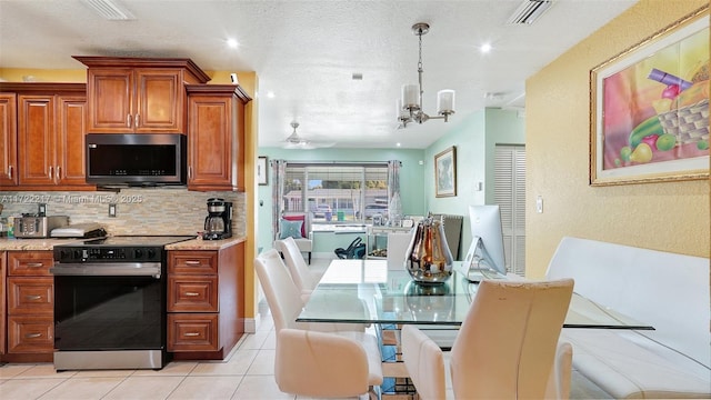 kitchen featuring light stone counters, a textured ceiling, decorative light fixtures, light tile patterned floors, and appliances with stainless steel finishes