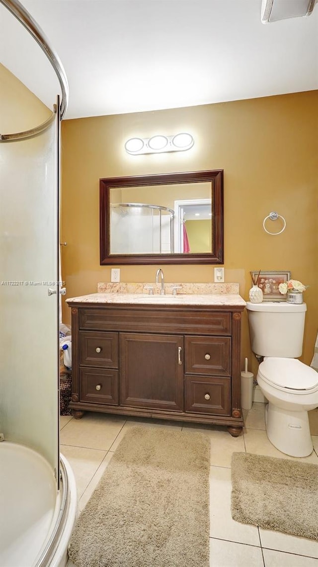 bathroom with tile patterned floors, vanity, toilet, and a shower with shower door