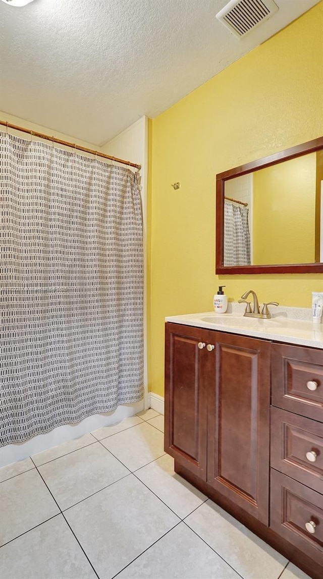 bathroom featuring curtained shower, tile patterned flooring, vanity, and a textured ceiling