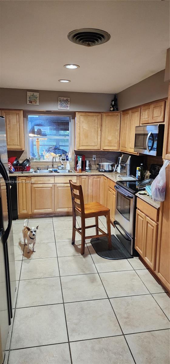 kitchen featuring sink, light tile patterned floors, and stainless steel appliances