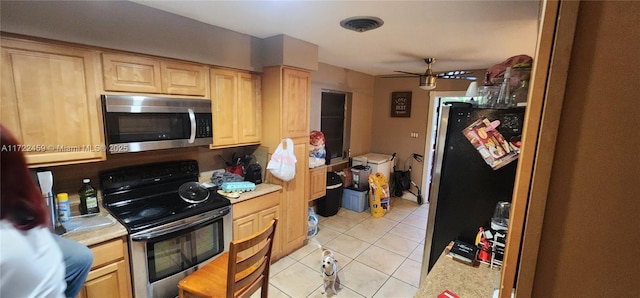 kitchen with light tile patterned flooring, electric stove, and light brown cabinetry