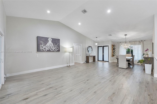 unfurnished living room with an inviting chandelier, light hardwood / wood-style flooring, and lofted ceiling