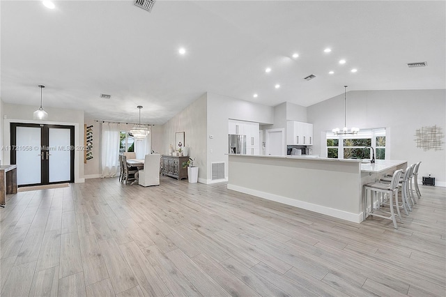 kitchen featuring white cabinets, stainless steel fridge with ice dispenser, light hardwood / wood-style floors, and a spacious island