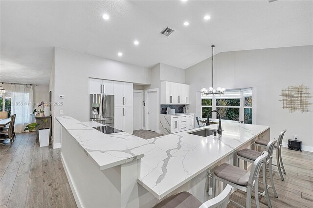 kitchen featuring stainless steel fridge, sink, white cabinets, and a spacious island