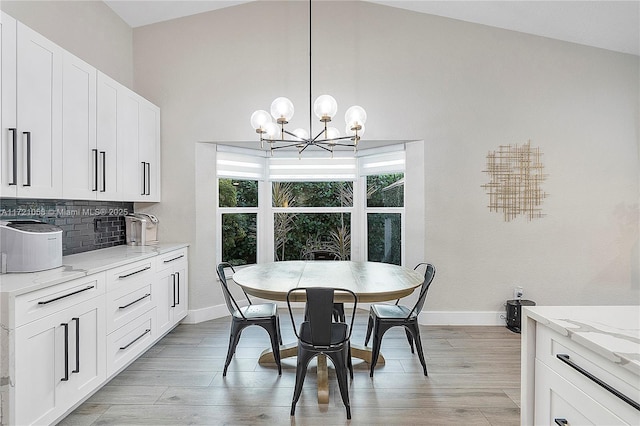 dining area featuring light wood-type flooring, vaulted ceiling, and a notable chandelier