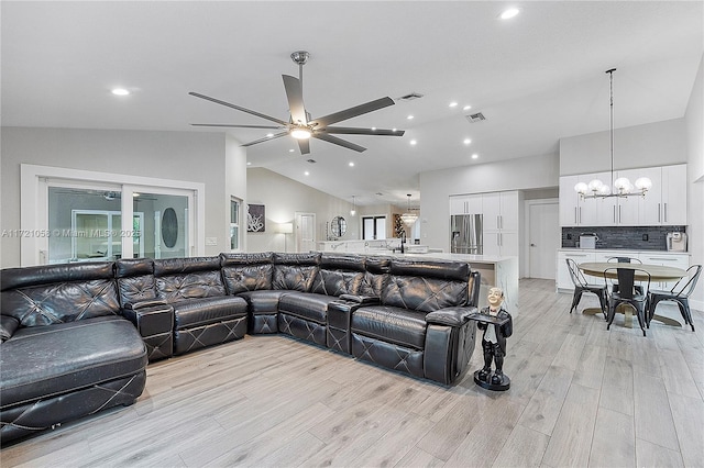 living room featuring ceiling fan with notable chandelier, sink, and vaulted ceiling