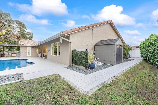 back of house with a fenced in pool, a patio area, and a storage shed