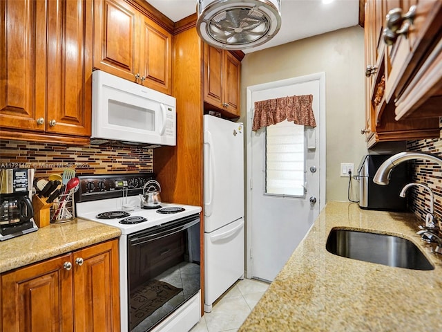 kitchen featuring backsplash, light stone counters, white appliances, and sink