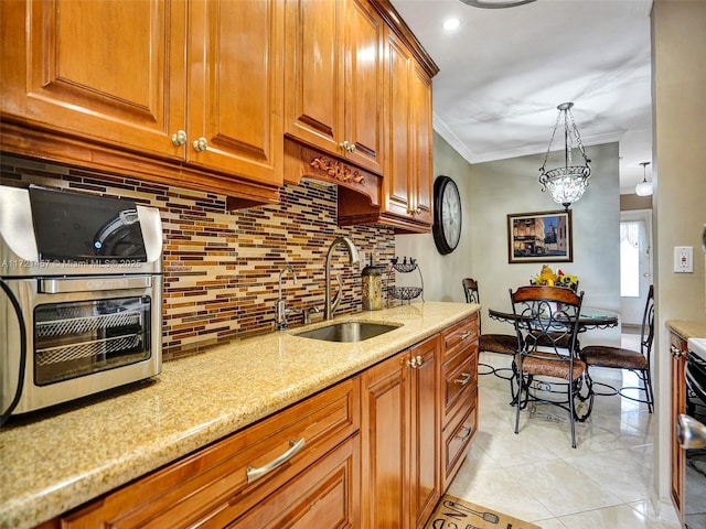 kitchen with sink, hanging light fixtures, tasteful backsplash, light stone counters, and crown molding