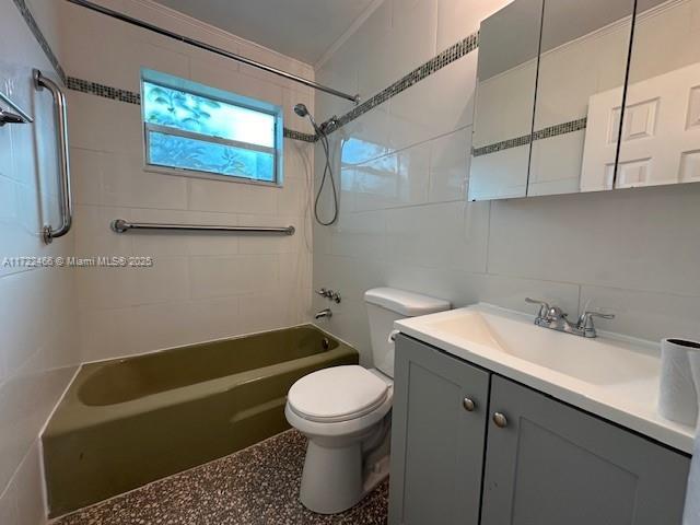 full bathroom featuring toilet, vanity, tile walls, and tiled shower / bath