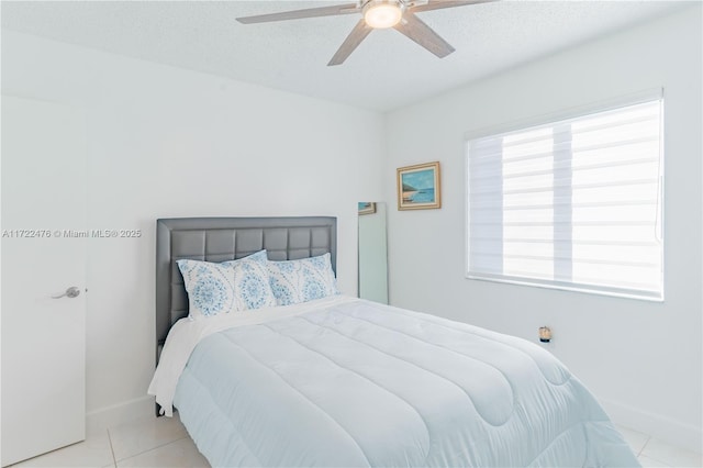 tiled bedroom with ceiling fan, a textured ceiling, and multiple windows