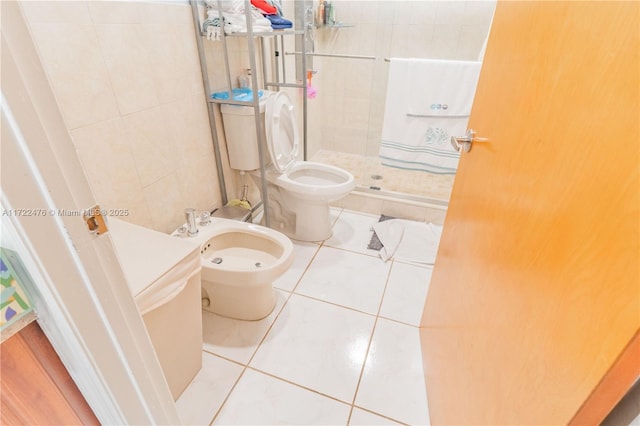 bathroom with tile patterned floors, a bidet, tile walls, toilet, and a shower with shower door