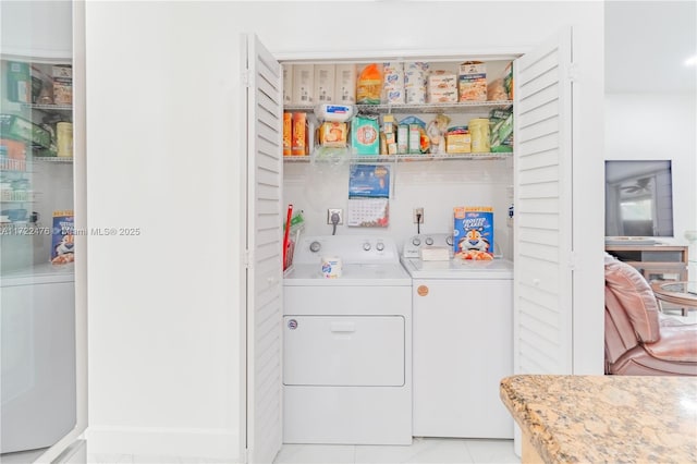 clothes washing area with light tile patterned floors and washer and clothes dryer