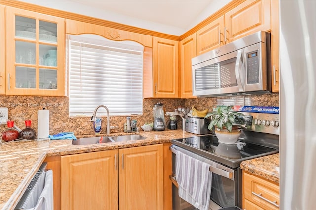 kitchen with sink, tasteful backsplash, light stone counters, light brown cabinetry, and appliances with stainless steel finishes