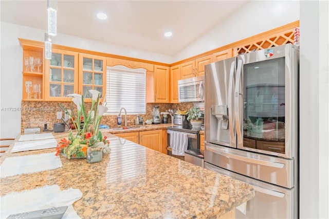 kitchen featuring light stone counters, light brown cabinets, stainless steel appliances, and sink