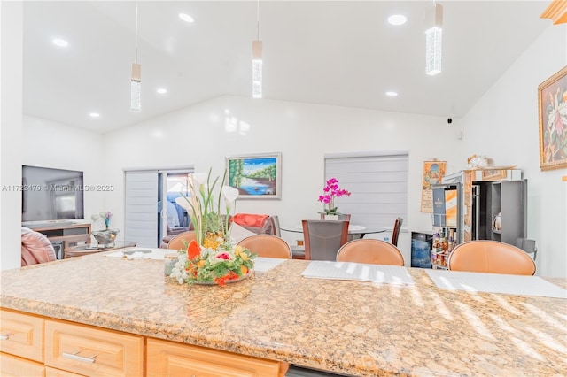 kitchen with stainless steel fridge, light brown cabinetry, vaulted ceiling, and hanging light fixtures