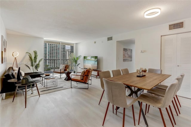 dining room featuring a wall of windows and light hardwood / wood-style flooring