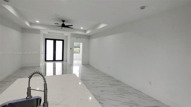 hall with french doors, a tray ceiling, and sink