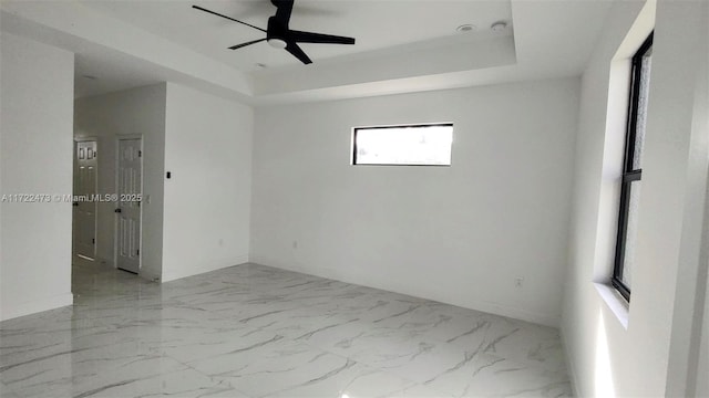 unfurnished room with a raised ceiling and ceiling fan