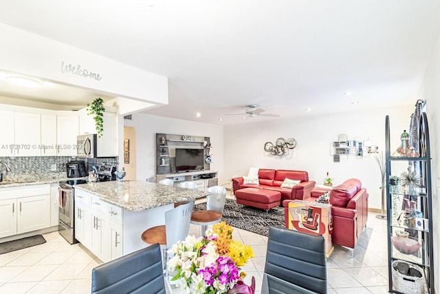 interior space with stainless steel appliances, ceiling fan, sink, light tile patterned floors, and white cabinets