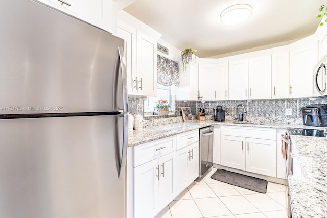 kitchen with light stone countertops, sink, stainless steel appliances, light tile patterned floors, and white cabinets