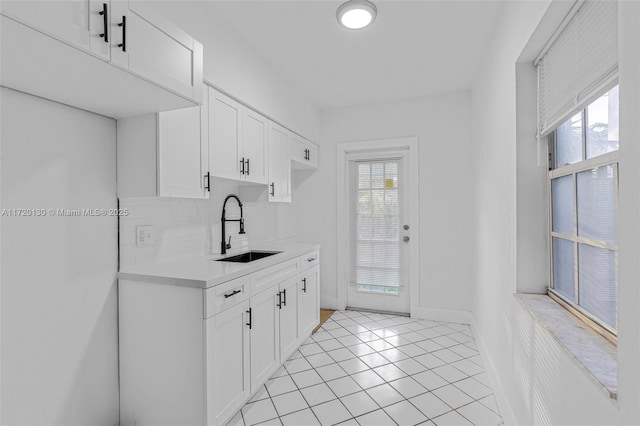 kitchen featuring backsplash, white cabinetry, sink, and light tile patterned floors