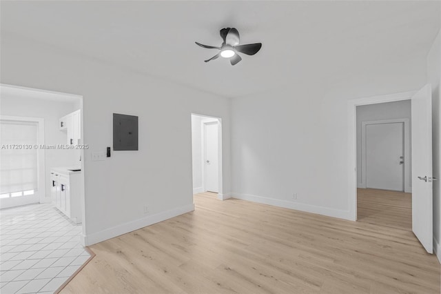 empty room with electric panel, ceiling fan, and light hardwood / wood-style flooring