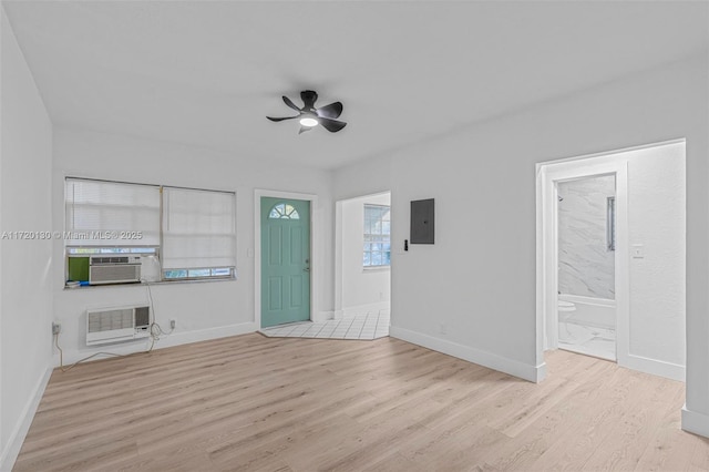 unfurnished living room with electric panel, cooling unit, ceiling fan, a wall mounted AC, and light hardwood / wood-style floors