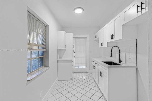 kitchen with tasteful backsplash, a wealth of natural light, sink, and white cabinets