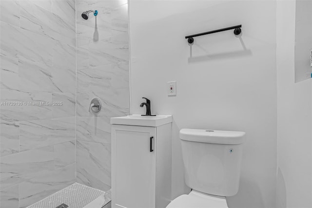 bathroom with tiled shower, vanity, and toilet