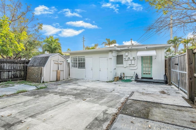 rear view of house with a storage shed and a patio