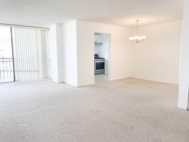 carpeted spare room featuring a textured ceiling, expansive windows, and a notable chandelier