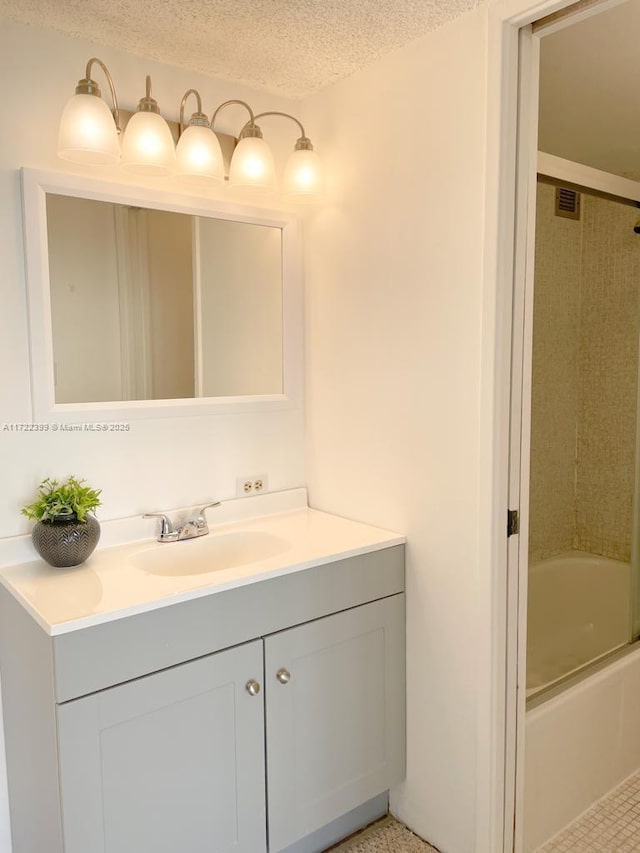 bathroom featuring a textured ceiling, vanity, and bath / shower combo with glass door