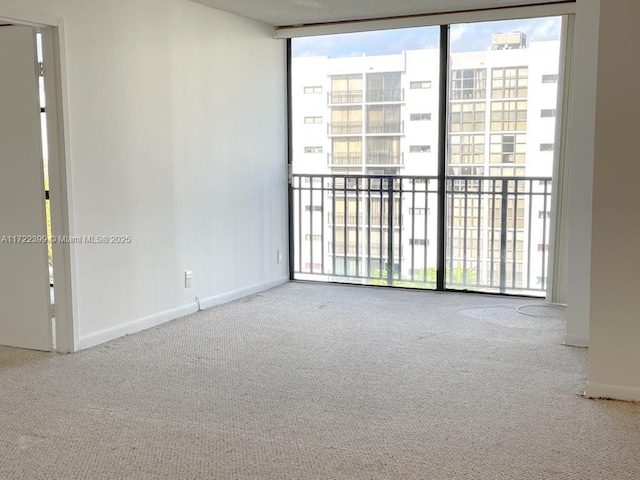 carpeted spare room with floor to ceiling windows