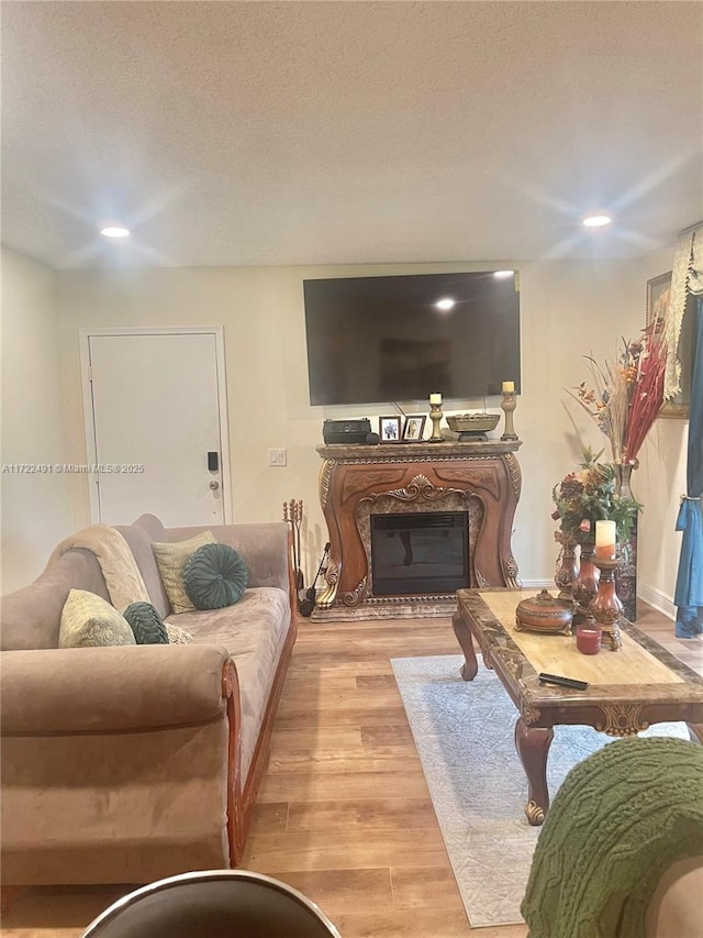 living room with a textured ceiling, a high end fireplace, and light hardwood / wood-style floors