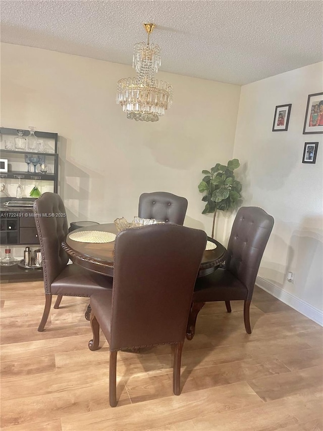 dining room featuring hardwood / wood-style flooring, a textured ceiling, and a notable chandelier