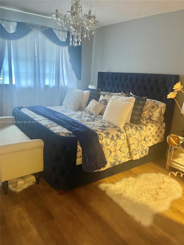 bedroom with a textured ceiling, wood-type flooring, and a notable chandelier