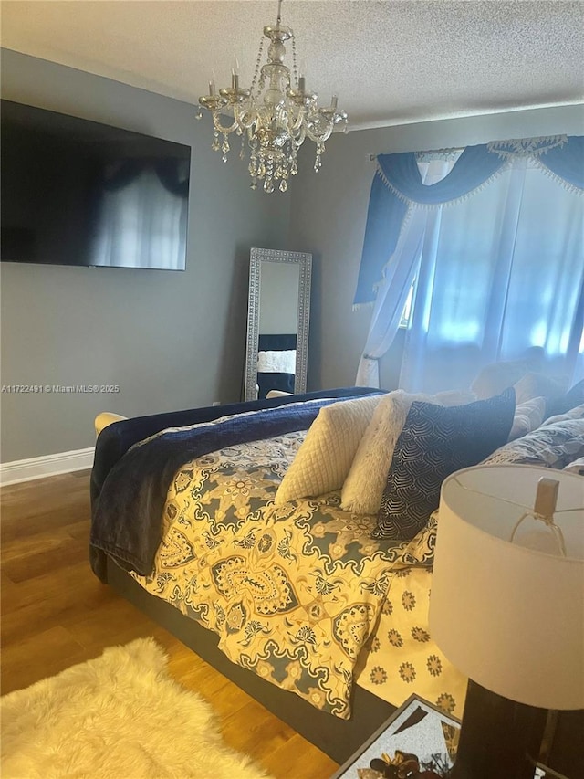 bedroom with hardwood / wood-style floors, a textured ceiling, and an inviting chandelier