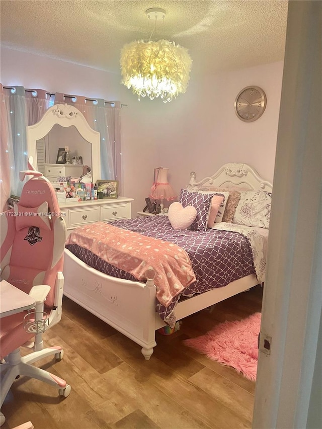 bedroom featuring light hardwood / wood-style floors, a textured ceiling, and a notable chandelier