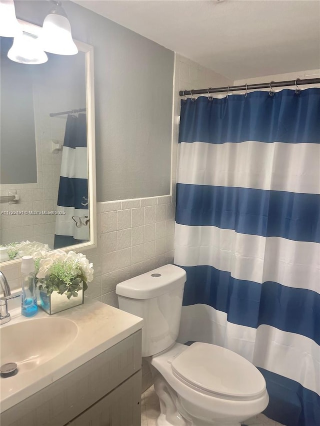 bathroom featuring tile walls, toilet, vanity, and a shower with shower curtain