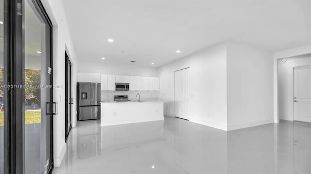 kitchen featuring white cabinets, appliances with stainless steel finishes, a center island with sink, and sink