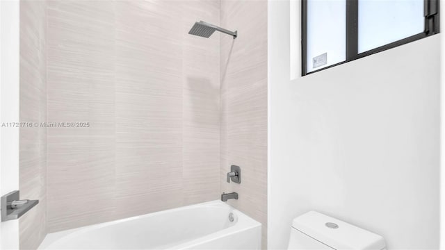 bathroom featuring tiled shower / bath combo and toilet